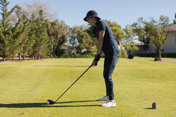 Senior man preparing to swing golf club on sunny course, enjoying outdoor activity, copy space