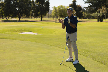 Senior man celebrating successful golf putt on sunny course, feeling joyful, copy space