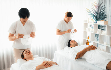 Fototapeta premium Serene modern daylight ambiance of spa salon, couple customer indulges in rejuvenating with facial skincare mask. Facial skin treatment and beauty cosmetology procedure for face. Quiescent