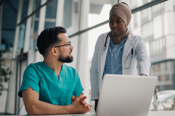 Doctors discussing patient data using laptop in hospital