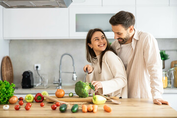 A playful moment in the kitchen as a couple joyfully prepares vegetables, showcasing their bond and love for cooking.