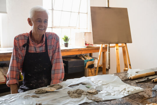 Senior man in art class creating pottery, smiling and enjoying creative therapy, copy space
