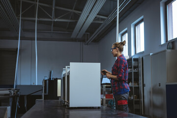 Female engineer operating machinery in modern factory, wearing safety glasses, copy space