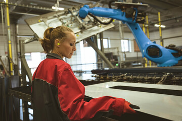 Female engineer operating machinery in modern factory, focused on precision work, copy space