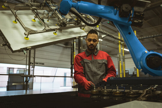Engineer operating robotic arm in modern factory, focusing on machinery controls, copy space