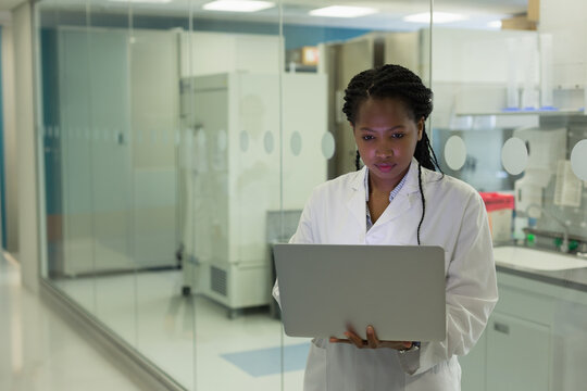 Scientist in lab coat analyzing data on laptop in modern laboratory, copy space