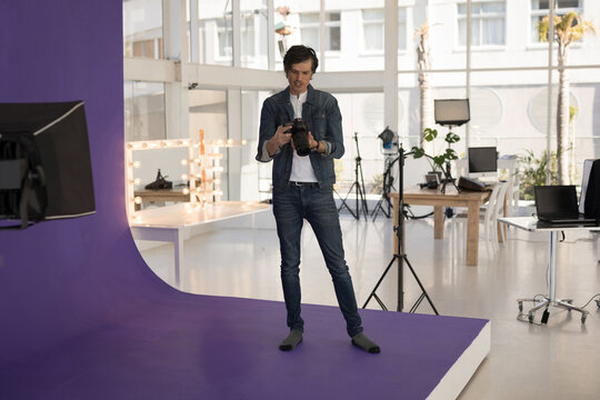 Photographer in studio adjusting camera settings, preparing for photo shoot