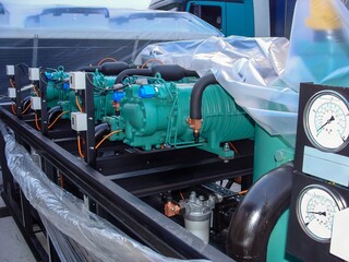 A row of modern turquoise industrial compressors are ready to be installed, safely wrapped in...
