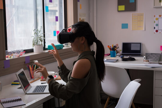 Fashion designer using VR headset and laptop in creative office workspace, copy space
