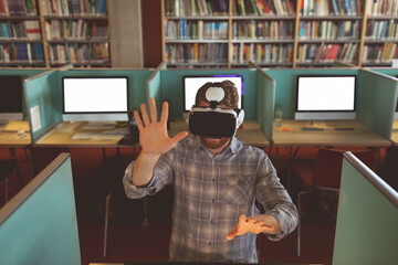 In library, man with VR headset at computer desk interacting with virtual world