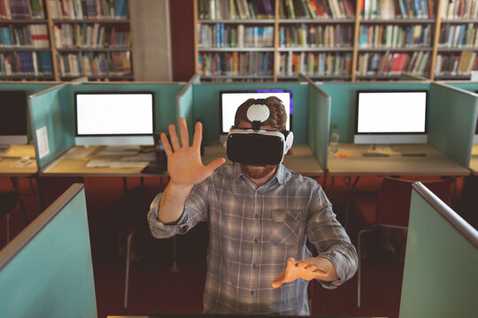 In library, man with VR headset at computer desk interacting with virtual world