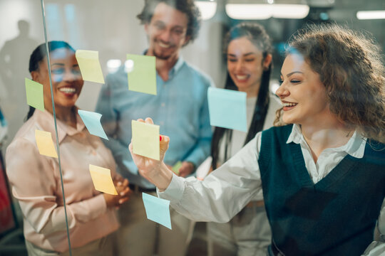 Business team brainstorming and planning using sticky notes on glass wall