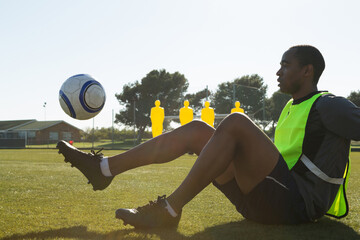 Practicing ball control, soccer player on field with training mannequins behind