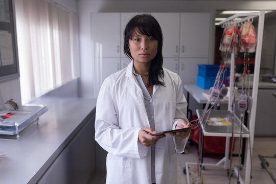 Scientist in lab coat analyzing data on tablet in medical laboratory