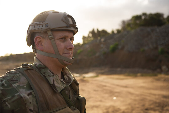 Military personnel in camouflage gear standing outdoors, focused and vigilant, copy space