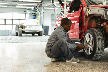 Mechanic repairing car wheel in auto workshop, focusing on precision work, copy space