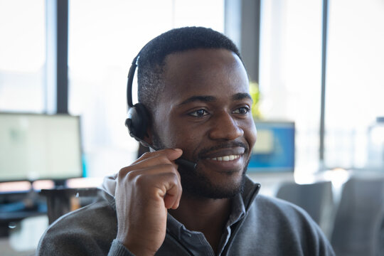 Customer service representative smiling while using headset in modern office