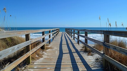 Fototapeta premium Coastal boardwalk jogging with ocean waves in the distance clear blue sky and spacious copy area