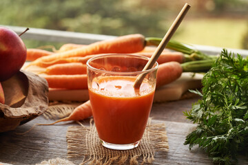 A glass of fresh carrot juice on a table with ecological bamboo straw