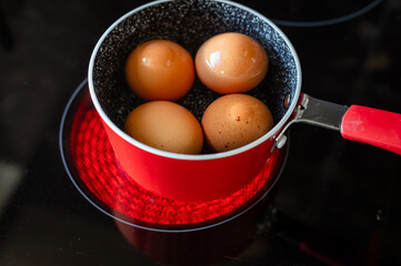 Red Saucepan with Boiling Eggs on an Electric Stove