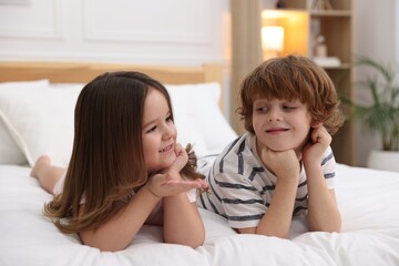Happy children wearing pajamas on bed at home