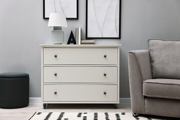 Dresser and other furniture near light grey wall in room. Interior design