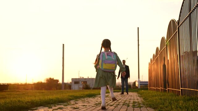 child runs into arms happy father. happy schoolboy spins his father arms. dream flying. girl runs through park with school backpack. father hugs child sunset. happy parent. Family man with kid girl.