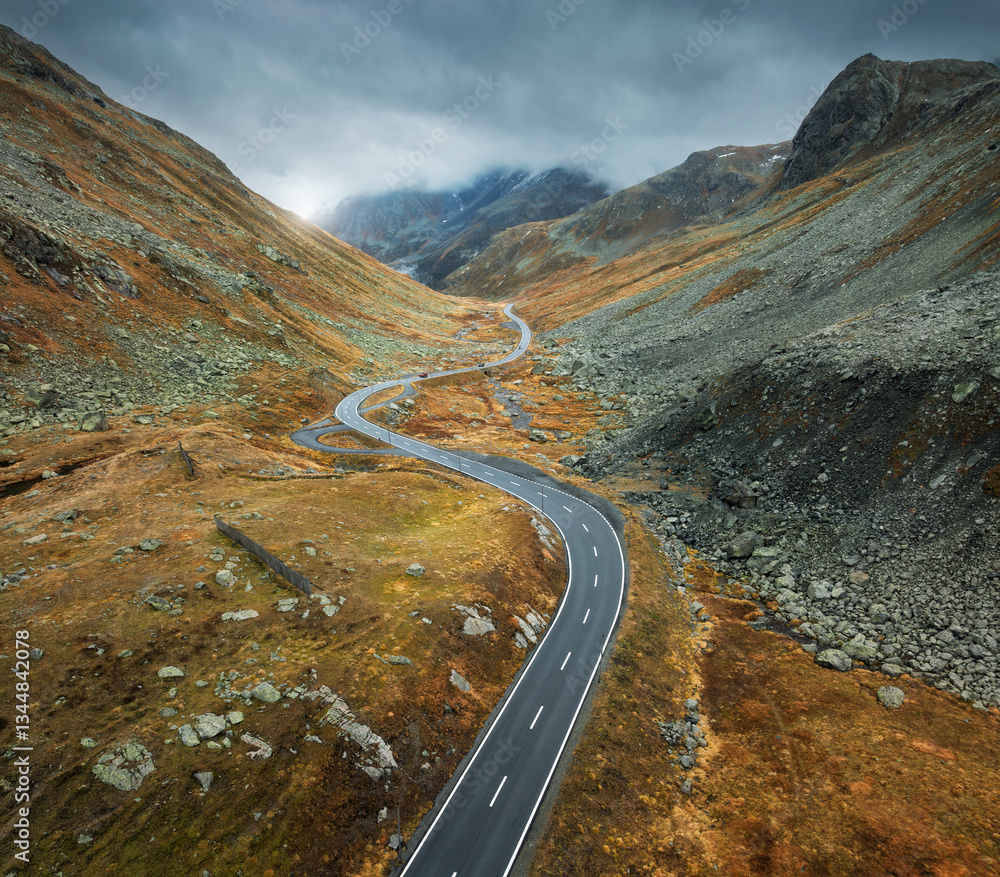 Wall mural aerial view of winding mountain road in alpine valley in cloudy autumn day in switzerland. top drone