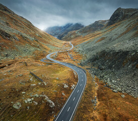 Aerial view of winding mountain road in alpine valley in cloudy autumn day in Switzerland. Top...