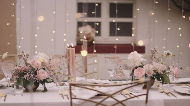 Wedding table in pastel colors with elegant decorations and yellow string lights 
