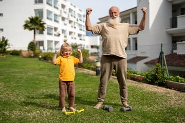 Grandfather and grandson showing their strength after a workout session