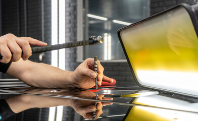 Removal of dents without painting. PDR technology for car body repair. PDR. The mechanic at the...