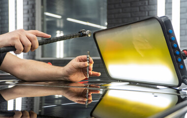 Removal of dents without painting. PDR technology for car body repair. PDR. The mechanic at the auto shop with tools to repair dents in car body. Body repair close-up.