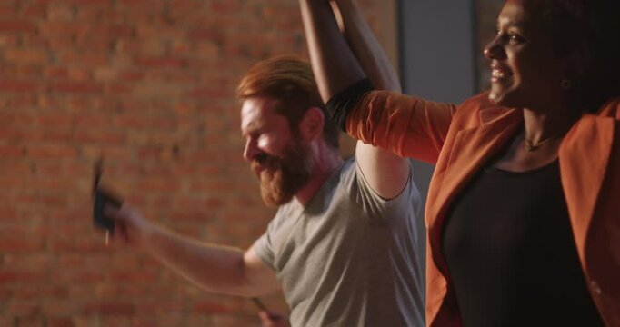 Man with red beard and African American woman holding hands dancing toward envelope offering during worship, smiling and laughing, diverse community in church, spiritual unity and joy