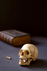 Artificial realistic human skull smoking a cigarette Copy space. Dark background