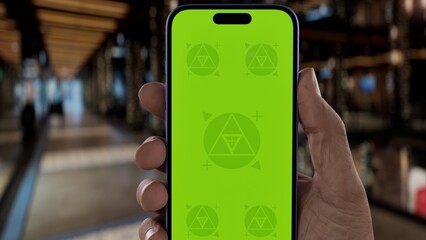 GREEN SCREEN CHROMA KEY A person holds a smartphone, festive shopping mall lights and Christmas decor in the background