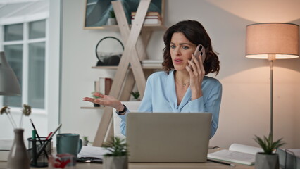 Frustrated executive speaking cellphone discussing papers at office closeup.