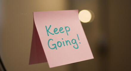A close-up of a motivational sticky note on a mirror with the words Keep Going! written in elegant handwriting. wide-angle shot, DSLR, natural light