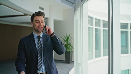Excited businessman calling smartphone in office corridor closeup. Happy manager