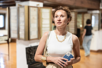Portrait of elegant thoughtful woman, wearing stylish gold jewelry and white top, contemplating...