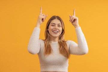 Smiling woman with arms raised pointing upwards