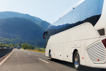Scenic back view big luxury white comfortable tourist bus driving through highway on bright sunny...
