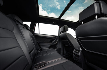Rear row of seats in a car. SUV or wagon interior with black leather seats and panoramic roof.
