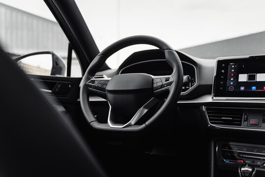 Modern car interior with metal accents. Steering wheel and dashboard of a new vehicle parked near warehouse.