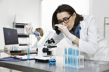 Scientist working with microscope and glassware in laboratory
