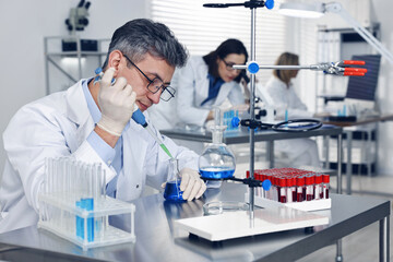 Scientist with micropipette and flask working in laboratory