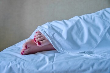 Her red-lacquered toes protrude from under a white cotton sheet. A woman does not want to wake up in the morning, she wants to sleep more.