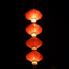 Illuminated red paper lanterns hanging together against the dark backdrop