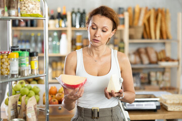 Woman carefully chooses delicious cheese in grocery department of a supermarket