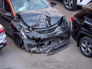A heavily damaged black car with a broken windshield and a crumpled front end after a serious...